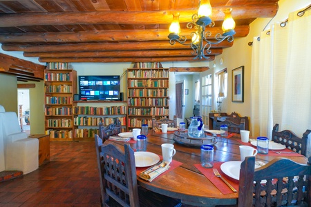 A dining table with plates and glasses in a room with bookshelves.