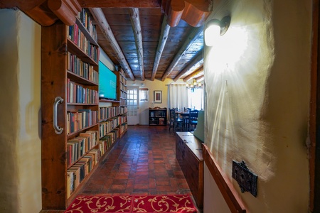 A hallway with bookshelves and a red rug.