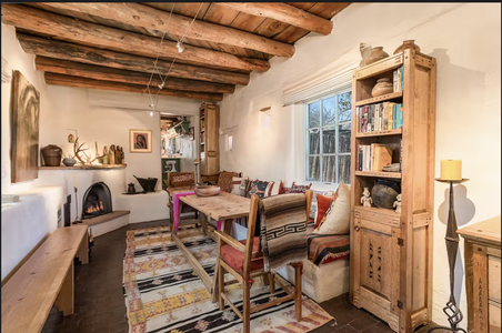 A living room with wooden beams and a fireplace.