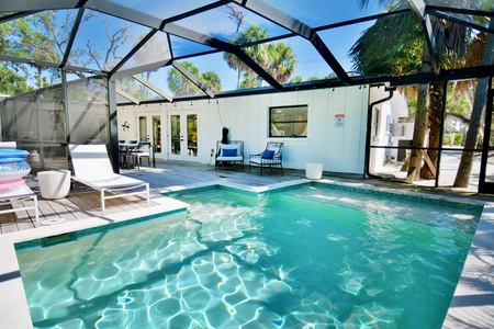 Outdoor patio area with a screened-in pool, seating and loungers