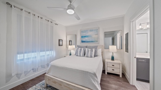 Relax in this serene coastal-inspired bedroom featuring a plush Queen bed, modern décor, and an en-suite bath for your comfort.