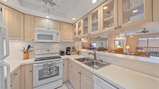 Kitchen fully equipped with coffee maker, appliances, cookware, utensils, and glassware.