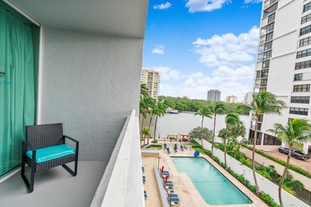 View from a balcony showing a pool area, palm trees, views of the intracoastal waterway.