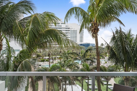 View of the resort through palm trees, featuring an amazing pool area with lounge chairs