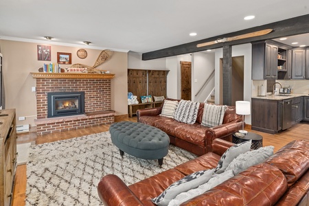 Fireplace, brown couches, grey ottoman, white rug.