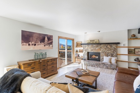 Beige couch, brown leather couch, television behind decretive sliding mural, fireplace, square coffee table, sliding glass door exiting onto porch.