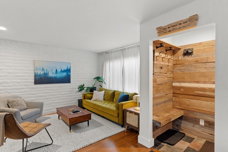 Entryway, yellow couch, long coffee table, two chairs.