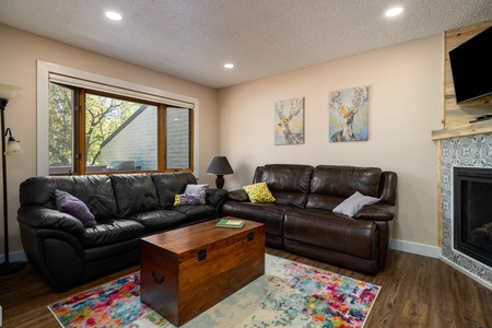 Black couch, brown table, fireplace, TV