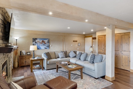 Large Beige "L" shaped pull-out couch, brown leather armchair with ottoman, wooden coffee table