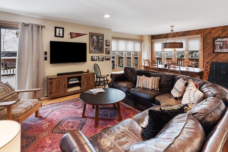 View of living room showing, couch, coffee table, arm chair, and large flat screen television. 