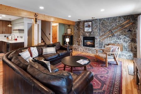 Photo of living room showing the leather couch, round coffee table, end table, wooden armchair and gas fireplace.