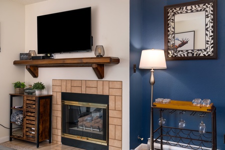 Photo of living room wall featuring a gas fireplace with wooden mantle and a flat screen smart TV above it.