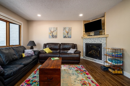 Black couch, brown table, fireplace, TV.