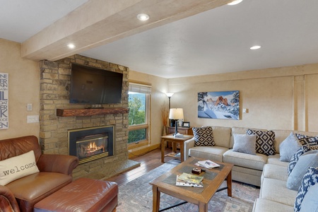 Brown leather armchair with ottoman, television, gas fireplace, wooden coffee table, beige sectional couch