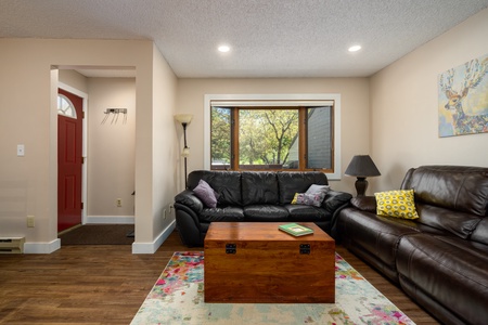 Black couch, brown table, large window, red door.