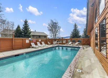 Large outdoor communal swimming pool with lounging chairs.