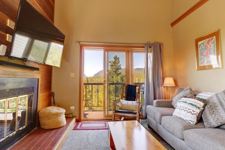 Cozy living room area offers a fireplace, TV, and access to private balcony with great mountain views.