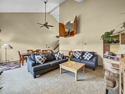 Large open concept living and dining area, featuring 2 sofas, a coffee table, tall ceilings, and ceiling fan.