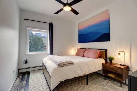 2nd bedroom features a queen cozy queen bed and a window offering natural light and views of mountains.