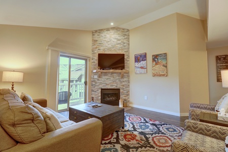 Nicely updated living room features a cozy fireplace, TV, and access to private deck.