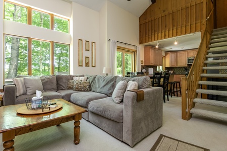 - Spacious living room with sectional sofa and tall windows - Natural light fills the space creating bright cozy atmosphere - Ideal for family relaxation after skiing hiking or exploring