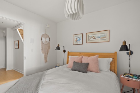 - Modern bedroom with white linens and framed art on bright walls   - Airbnb stay provides cozy pillows and lighting for restful nights   - Vacation rental includes stylish bedroom with window drapes