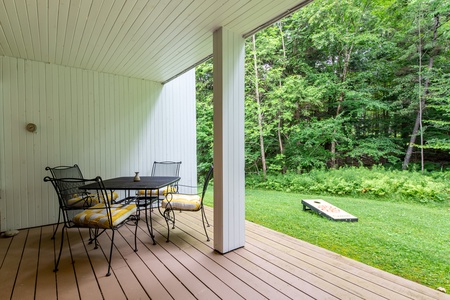 Covered back deck with a grill, outdoor dining table, and lawn games - perfect for cookouts and summer fun.