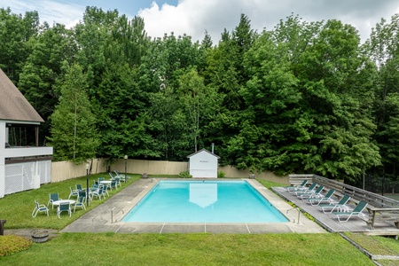 - Large outdoor swimming pool surrounded by lounge chairs and trees   - Refreshing summer retreat perfect for family and friends   - Relax, swim, and soak up the sunshine in peaceful mountain setting