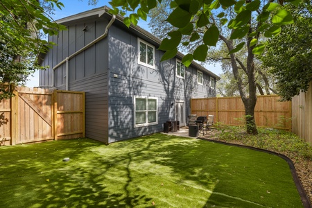 Fenced backyard with turf, grill, seating, fire pit