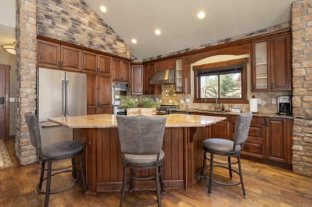 A modern kitchen with wooden cabinets, a central island with bar stools, stainless steel appliances