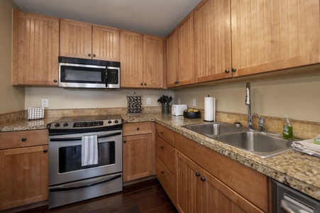 A kitchen with wooden cabinets, stainless steel appliances, granite countertops, a double sink,