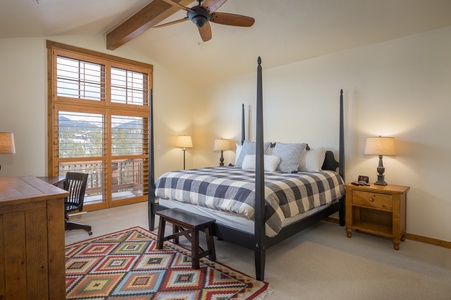 - Spacious bedroom with a king bed and rustic wood accents for comfort   - Natural light fills the room with mountain views through wide windows   - Cozy design with ceiling fan and vibrant rug makes restful nights inviting
