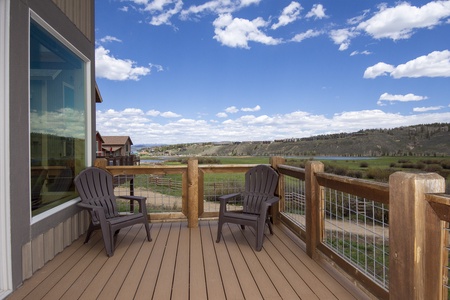 A wooden deck with outdoor furniture overlooks a scenic landscape