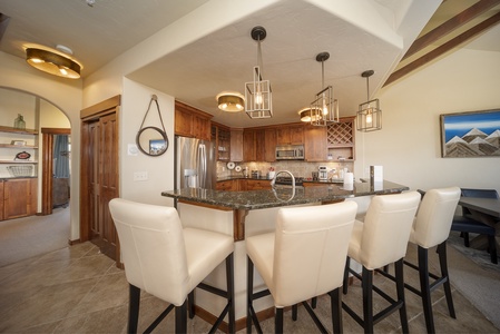 - Kitchen bar with seating for four and pendant lighting above   - Stainless steel appliances and stone counters for easy cooking   - Open design connects to dining and living for shared meals