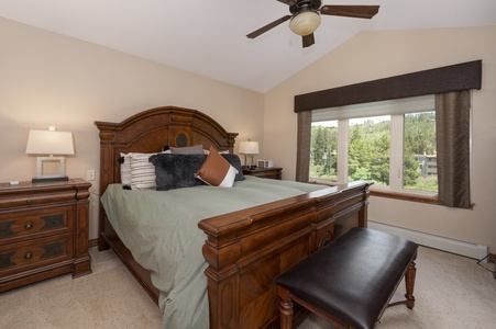 - Bedroom with vaulted ceiling and large window view   - Warm wooden furniture complements mountain style   - Comfortable retreat with modern rustic touches