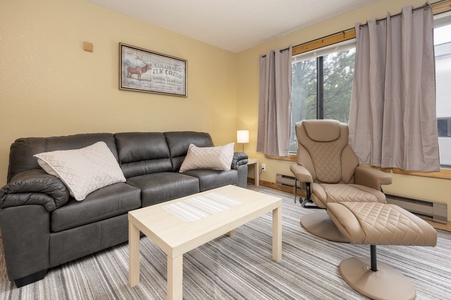 A spacious living room with a leather sofa a TV and windows that bathe the space in natural light