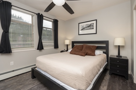 - Bedroom with queen bed, ceiling fan, and large windows inside   - Comfortable bedding provides restful sleep for all guests   - Cozy mountain retreat perfect for couples or solo travelers