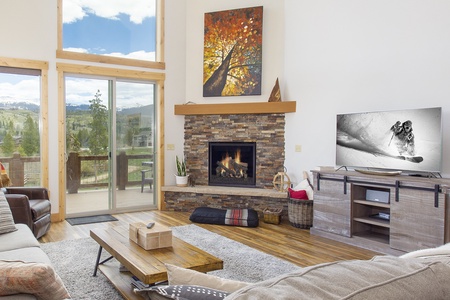 A modern living room features a stone fireplace, a wall-mounted TV with cool modern decor