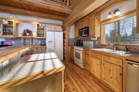 - Spacious log cabin kitchen with wood cabinetry style   - Modern appliances include stove fridge and microwave   - Fully equipped for cooking meals after outdoor fun