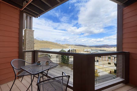 A balcony with a metal railing overlooks a mountainous landscape.