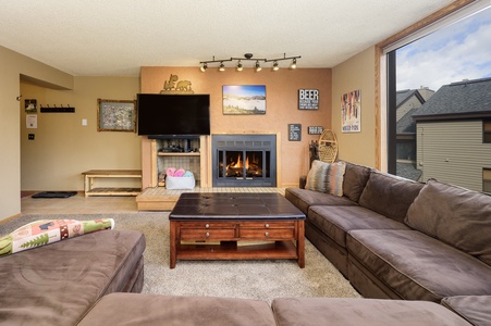 The living room features a  sectional sleeper sofa, a fireplace and large windows