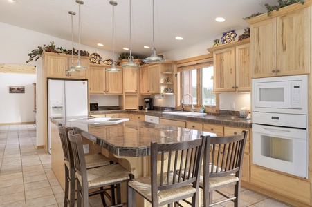 A spacious kitchen with lots of cabinet space and ample seating, stocked with all your culinary needs