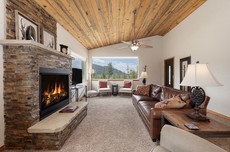 Spacious living area with plenty of seating around the cozy fireplace, the wooden ceiling gives you that mountain cabin feel.