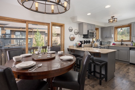 A dining area with modern lighting and a breakfast nook lead to the kitchen