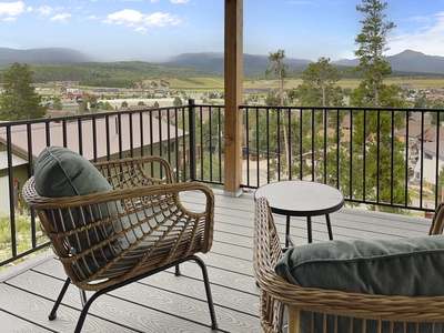 Outdoor deck with wicker chairs and a small table overlooking the scenic valley