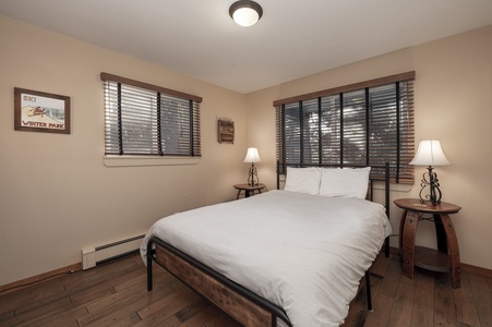 A bedroom with a Queen size bed, and windows bathing the space in natural light