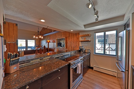 Modern kitchen with dark countertops, stainless steel appliances, and track lighting.