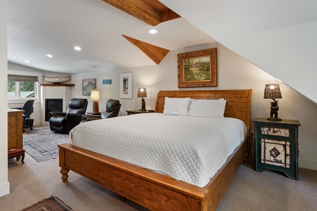 - Spacious bedroom featuring wooden frame king bed and calming design   - Soft lighting and rustic accents create a warm and restful atmosphere   - Peaceful retreat with seating area and cozy touches for mountain stays