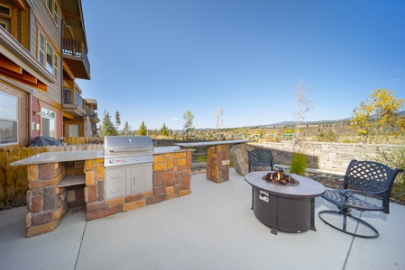 Outdoor patio with a built-in stone gas barbecue grill, a metal fire pit, perfect for sunlit afternoons or starlit nights