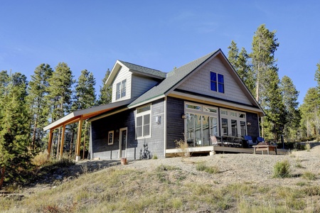 The carriage house has a large deck with Adirondack chairs and an outdoor dining table.